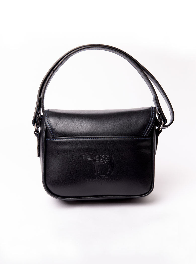 Flat lay of a small premium bridle butt navy leather crossbody Faith hand bag that has been hand stitched in England with 1 front facing buckle strap and the back embossed with Newmarket 875 horse logo.