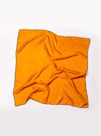 Flat lay of 100% silk 90x90 foulard scarf in gold yellow with navy hand stitched border. 