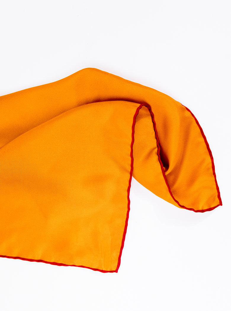 Flat lay of 100% silk 40x40 hank scarf in gold yellow with red hand stitched border. 