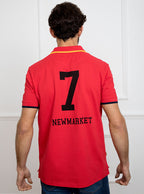 Man wearing red polo shirt in 100% cotton with Newmarket 875 crest embroidered on the front with navy sleeve trimming and gold collar trimming.
