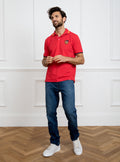 Man wearing red polo shirt in 100% cotton with Newmarket 875 crest embroidered on the front with navy sleeve trimming and gold collar trimming.
