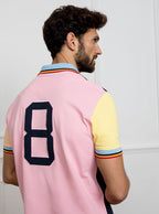 Man wearing navy based multicoloured panelled 100% cotton polo shirt with giant number 8 on pale pink back.