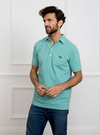 Man wearing avocado green polo shirt in 100% cotton with Newmarket 875 horse logo embroidered on the front.