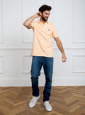 Man wearing peach coloured polo shirt in 100% cotton with Newmarket 875 horse logo embroidered on the front.