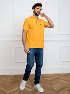 Man wearing gold yellow polo shirt in 100% cotton with Newmarket 875 horse logo embroidered on the front.