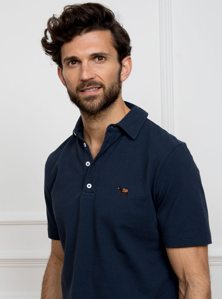 Man wearing navy blue polo shirt in 100% cotton with Newmarket 875 horse logo embroidered on the front.
