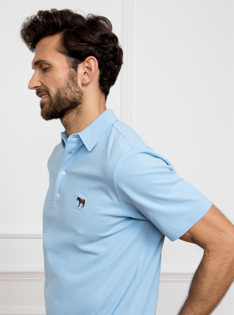 Man wearing sky blue polo shirt in 100% cotton with Newmarket 875 horse logo embroidered on the front.