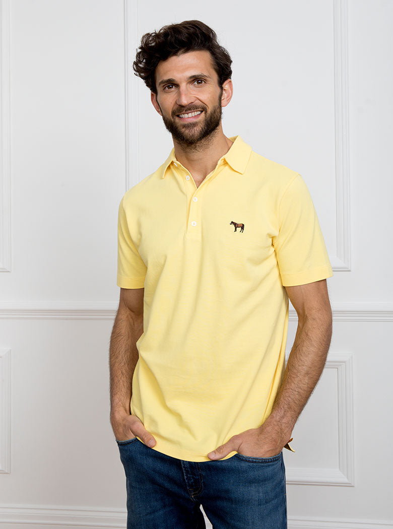 Man wearing lemon yellow polo shirt in 100% cotton with Newmarket 875 horse logo embroidered on the front.
