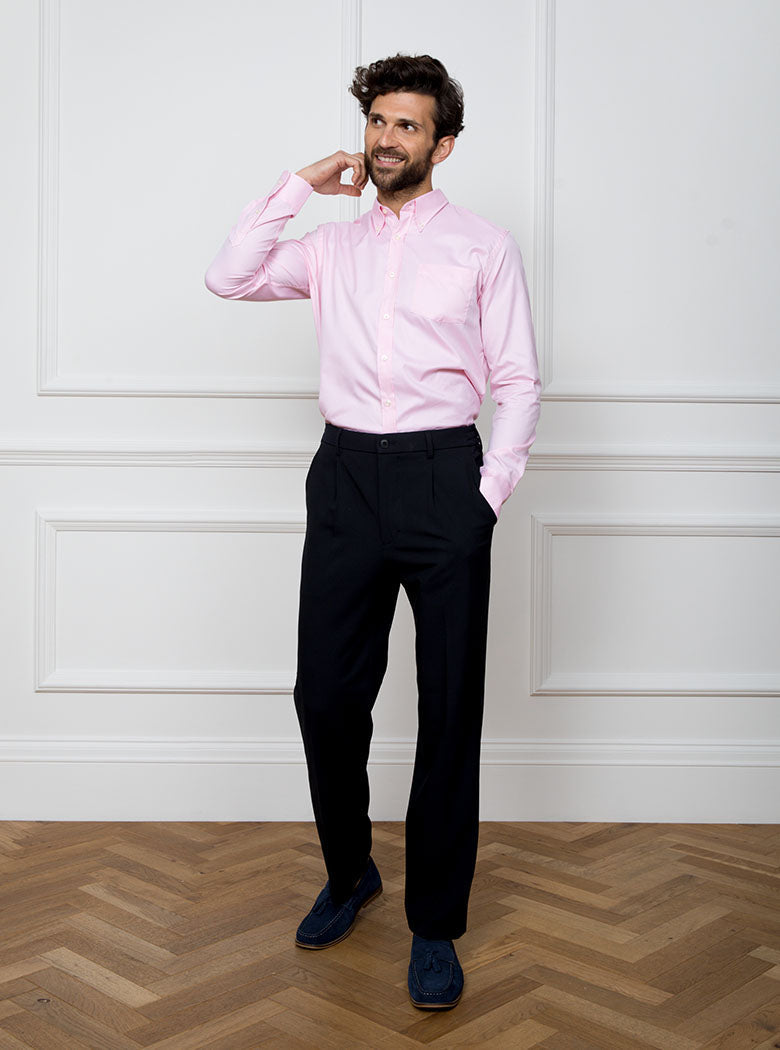 Man wearing a pale pink long sleeved shirt with a button down collar made with 100% Royal Oxford Cotton.