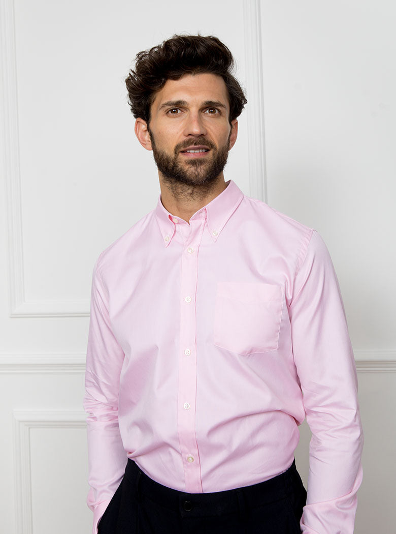 Man wearing a pale pink long sleeved shirt with a button down collar made with 100% Royal Oxford Cotton.