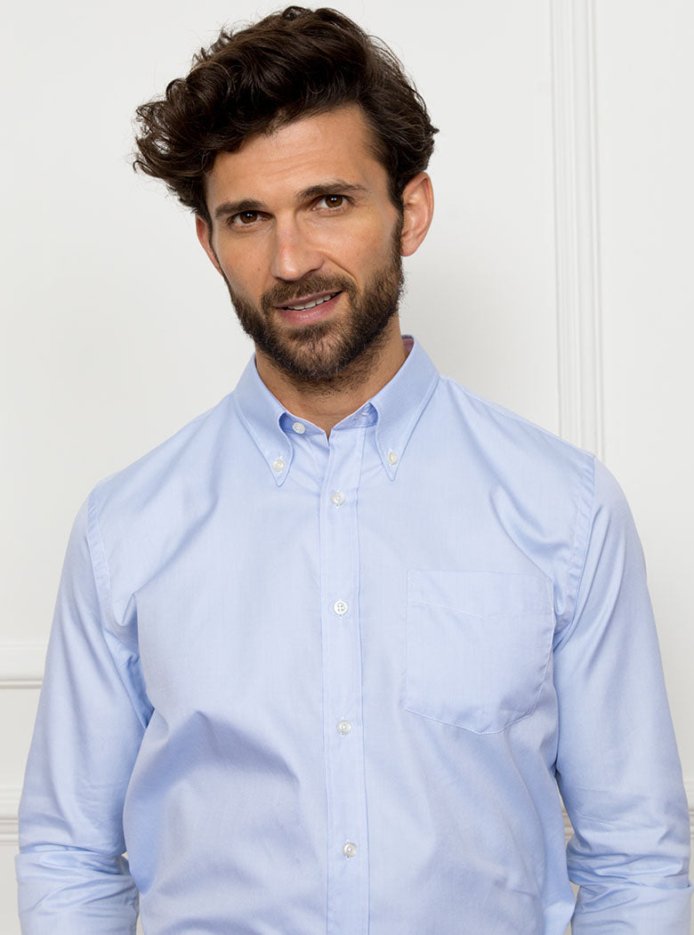 Man wearing a sky blue long sleeved shirt with a button down collar made with 100% Royal Oxford Cotton.
