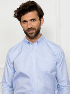 Man wearing a sky blue long sleeved shirt with a button down collar made with 100% Royal Oxford Cotton.