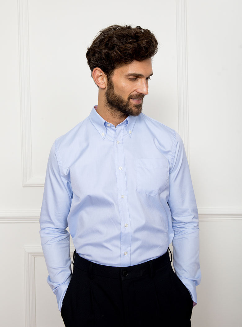 Man wearing a sky blue long sleeved shirt with a button down collar made with 100% Royal Oxford Cotton.