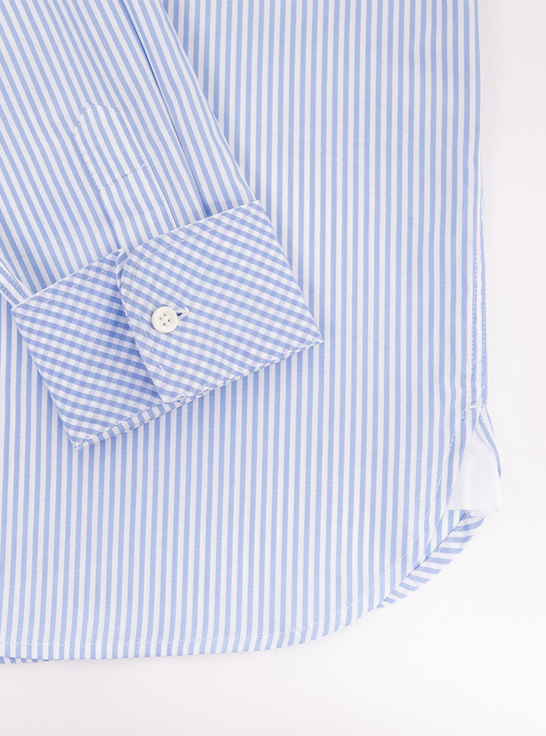 Flat lay of mans long sleeved shirt in thin stripe sky blue and white print with inside of collar and cuff in gingham pattern. Made with 100% cotton in Thomas Mason fabric.
