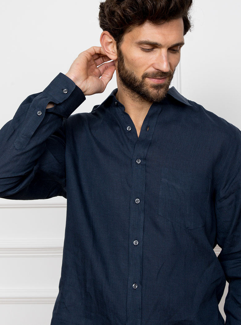 Man wearing a navy blue long sleeved shirt with pocket detail made with 100% linen in a Thomas Mason fabric.