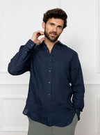Man wearing a navy blue long sleeved shirt with pocket detail made with 100% linen in a Thomas Mason fabric.