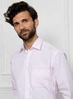 Man wearing long sleeved shirt with pale pink and white stripe made with 100% cotton from Thomas Mason.