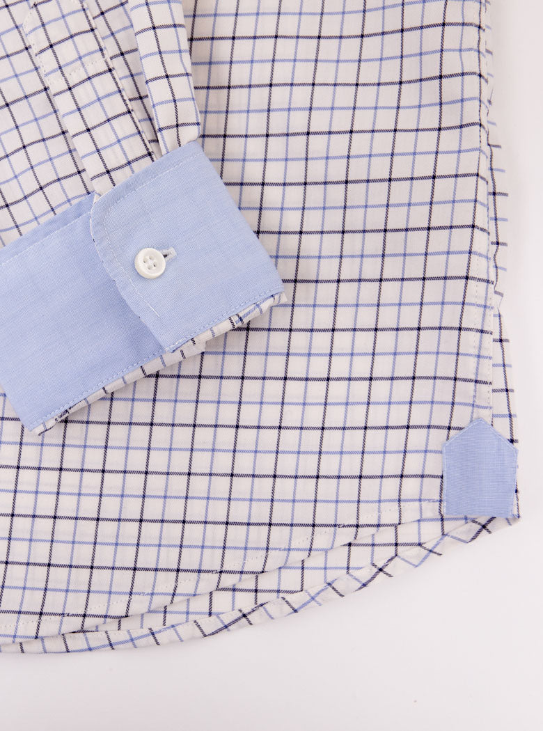 Flat lay of long sleeved shirt with tattersall blue check pattern and the inside collar and cuffs trimmed with sky blue. Made with 100% cotton in Thomas Mason fabric.