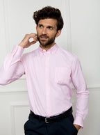 Man wearing a long sleeved shirt with a pale pink and white thin stripe pattern made with 100% Oxford in a Thomas Mason fabric.