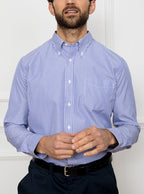 Man wearing long sleeved shirt with royal blue and white thin stripe made with 100% cotton from Thomas Mason.
