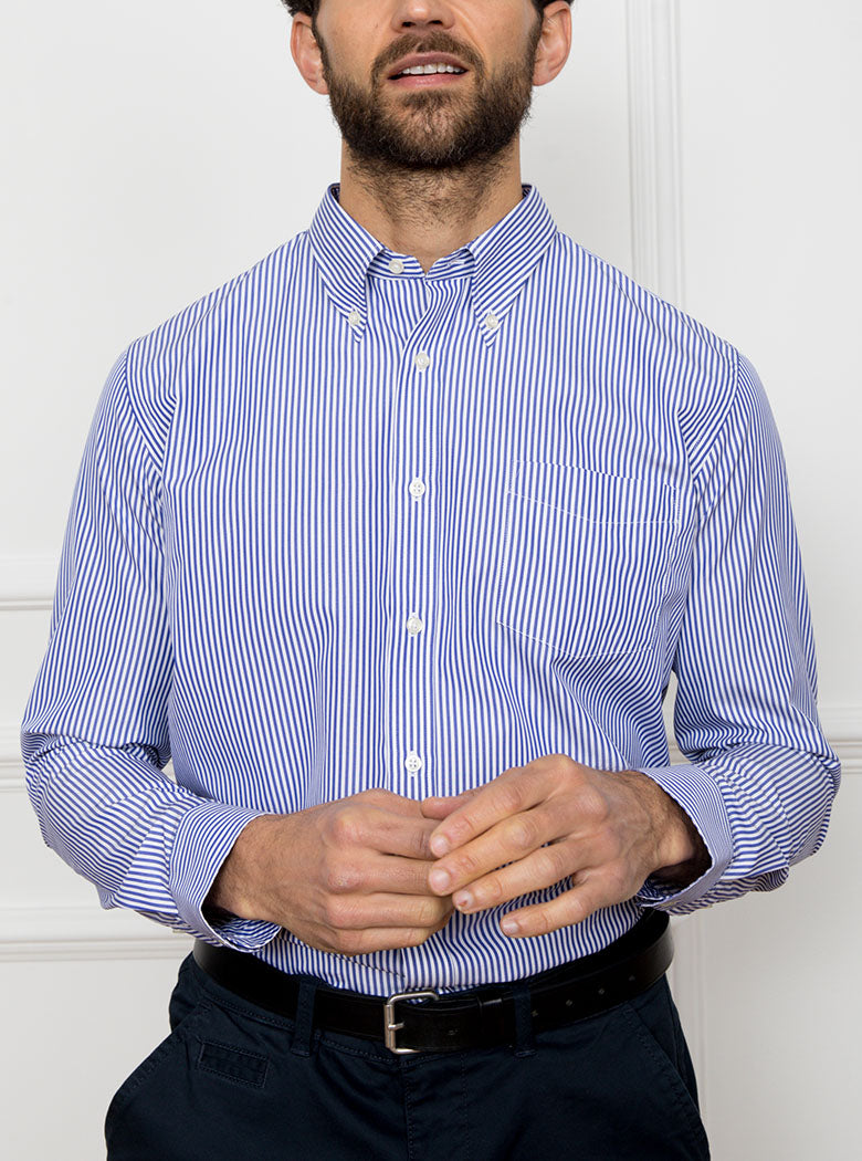 Man wearing long sleeved shirt with royal blue and white thin stripe made with 100% cotton from Thomas Mason.