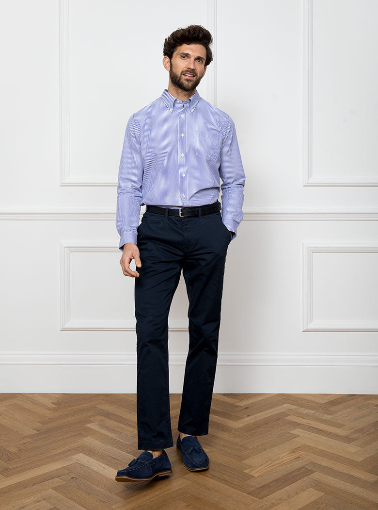 Man wearing long sleeved shirt with royal blue and white thin stripe made with 100% cotton from Thomas Mason.