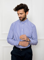 Man wearing long sleeved shirt with royal blue and white thin stripe made with 100% cotton from Thomas Mason.