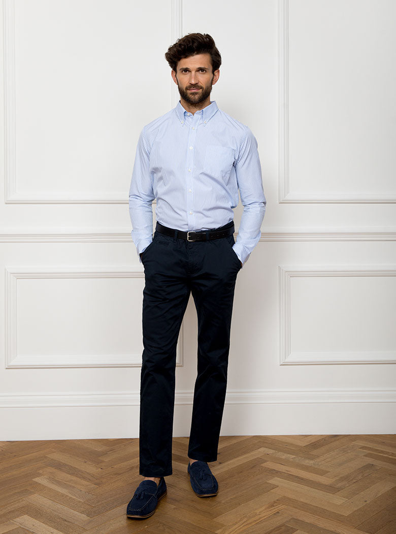 Man wearing long sleeved shirt with sky blue and white thin stripe and the inside collar and cuffs trimmed with gingham pattern. Made with 100% cotton in Thomas Mason fabric.