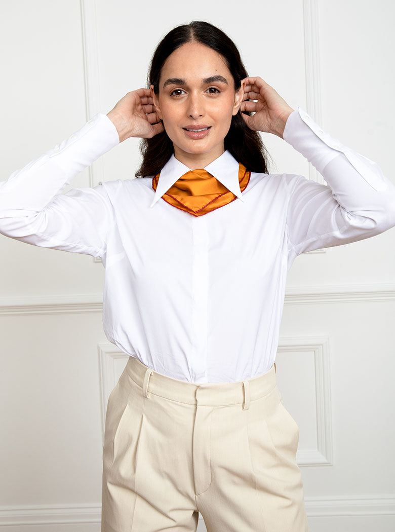 Woman wearing 100% silk 40x40 hank scarf in gold yellow with red hand stitched border. 
