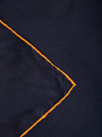Flat lay of 100% silk 40x40 hank scarf in navy with gold yellow hand stitched border. 