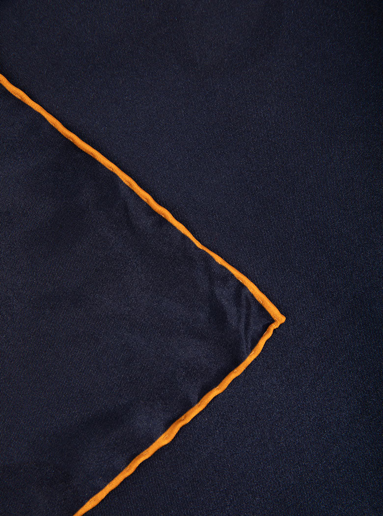 Flat lay of 100% silk 40x40 hank scarf in navy with gold yellow hand stitched border. 