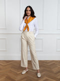 Woman wearing 100% silk 90x90 foulard scarf in gold yellow with navy hand stitched border. 