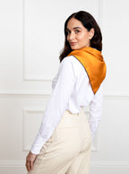 Woman wearing 100% silk 90x90 foulard scarf in gold yellow with navy hand stitched border. 